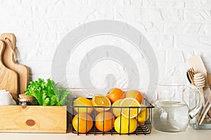 Shelf in a white kitchen with fresh fruits, herbs, cutlery, kitchen utensils, tools, textiles, fresh water in a decanter
