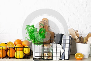 Shelf in a white kitchen with fresh fruits, herbs, cutlery, kitchen utensils, tools, textiles, fresh water in a decanter