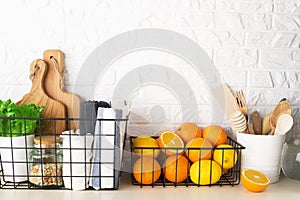 Shelf in a white kitchen with fresh fruits, herbs, cutlery, kitchen utensils, tools, textiles, fresh water in a decanter