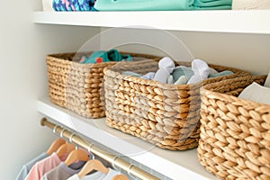 shelf with woven baskets storing socks and onesies in a nursery