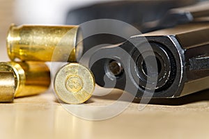 Shell casings and barrel of a pistol close-up on a wooden table in a shooting range or at a crime scene. crime concept
