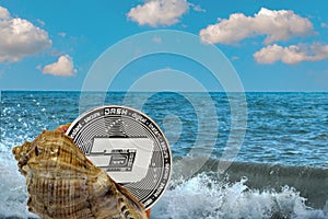 Shell with a Dash cryptocurrency coin on the background of sea waves and the ocean.
