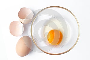 Shell with egg and open Eggs in a bowl on white background. Top view closeup