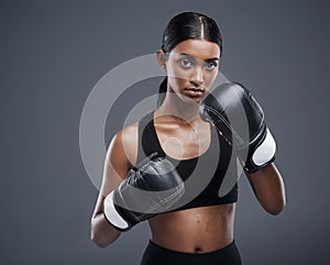 Shell knock you out with just one blow. Studio portrait of a sporty young woman wearing boxing gloves against a grey