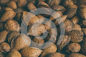 Shelled almonds nuts as background. Heap of almonds texture and background for design. Close up view of almonds in their shells.