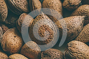 Shelled almonds nuts as background. Heap of almonds texture and background for design. Close up view of almonds in their shells.