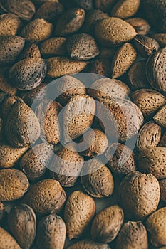 Shelled almonds nuts as background. Heap of almonds texture and background for design. Close up view of almonds in their shells.