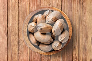 Shelled pecan nuts raw in bowl on wooden table background, top view. organic vegetarian food