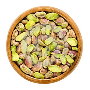 Shelled pistachio kernels in wooden bowl over white