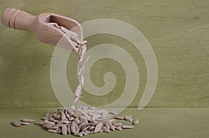 Shelled sunflower seeds falling from a small wooden spoon.