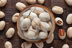 Shelled, vanilla fried pecan nuts in wooden bowl, top view