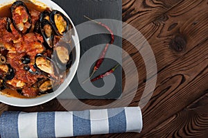 Shellfish seafood. Hot fresh italian appetizing steamed mussels in tomato sauce with olives and red pepper on vintage wooden table