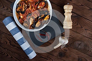 Shellfish seafood. Hot fresh italian appetizing steamed mussels in tomato sauce with olives and red pepper on vintage wooden table