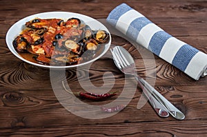 Shellfish seafood. Hot fresh italian appetizing steamed mussels in tomato sauce with olives and red pepper on vintage wooden table