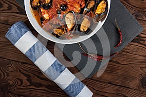 Shellfish seafood. Hot fresh italian appetizing steamed mussels in tomato sauce with olives and red pepper on vintage wooden table