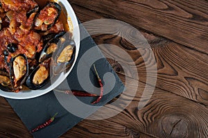 Shellfish seafood. Hot fresh italian appetizing steamed mussels in tomato sauce with olives and red pepper on vintage wooden table