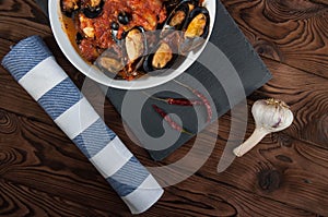 Shellfish seafood. Hot fresh italian appetizing steamed mussels in tomato sauce with olives and red pepper on vintage wooden table