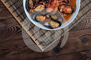 Shellfish seafood. Hot fresh italian appetizing steamed mussels in tomato sauce with olives and red pepper on vintage wooden table