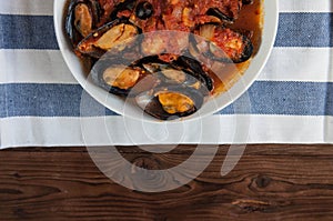 Shellfish seafood. Hot fresh italian appetizing steamed mussels in tomato sauce with olives and red pepper on vintage wooden table