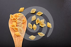 Shells pasta in a ladle, black background