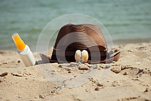 Shells and sunglasses on a hat and a bottle of sunscreen lotion