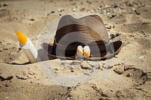 Shells and sunglasses on a hat and a bottle of sunscreen lotion