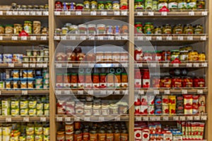 Shelves with canned foods in the supermarket. Blurred