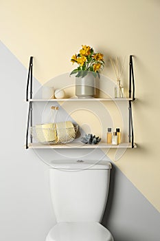 Shelves with different stuff on wall above toilet bowl