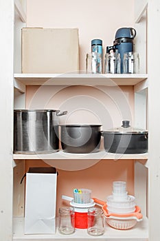 Shelving in the pantry with home cooking utensils and boxes close-up