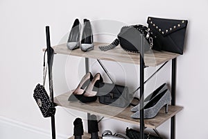 Shelving unit with stylish shoes and purses near white wall.