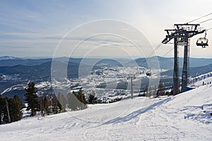 Sheregesh Winter ski resort in Russia. Skiers and snowboarders move on a lockable chair ski lift. Mountains, view of the