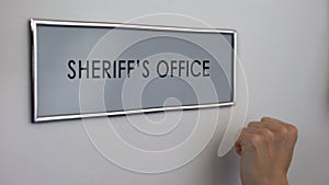 Sheriff office door, hand knocking, law enforcement officer, crime prevention photo