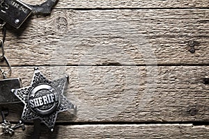 Sheriff star and handcuffs on wooden table photo