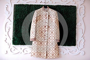 A sherwatni kurta for Indian groom.  on wall in green background