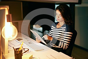 Shes as equally productive through the day and night. Shot of a young businesswoman working late on a digital tablet in