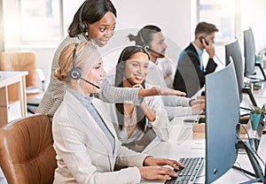 Shes an awesome and helpful supervisor. a group of female call center agents wearing headsets and working together on a