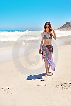 Shes a beach lover. a sexy young woman walking on the beach.