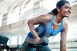 Shes a beauty and a beast. an attractive young woman working out with dumbbells at the gym.