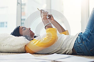 Shes been studying all day, now for a break. a young female student using a cellphone while studying at home.