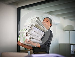 Shes bitten off more than she can chew. Portrait of a hardworking businesswoman struggling to carry a heap of files in