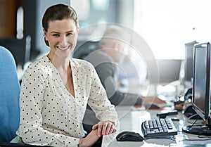 Shes climbing the ladder of success. Portrait of a young woman working at her computer in an office with colleagues in