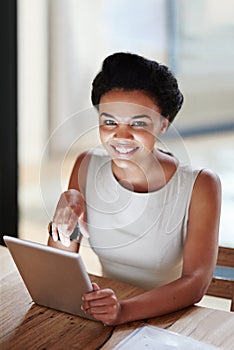 Shes a connected exec. Portrait of a smiling young businesswoman using a digital tablet in an office. photo