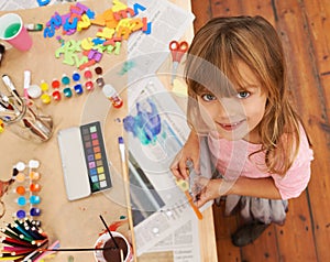 Shes so creative. a little girl looking up while doing arts and crafts.