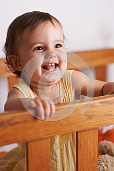 Shes so cute and happy. A cute litlle baby girl laughing as she stands up in her crib.