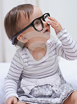 Shes destined for great things. A cute little baby girl wearing over-sized spectacles.