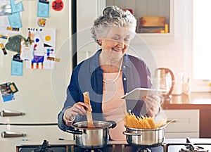 Shes digitised all her recipes for easier access and usage. a senior woman using a digital tablet while cooking in her