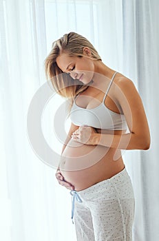 Shes due any time now. a beautiful woman touching her pregnant belly.
