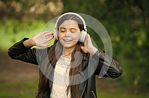 Shes ear for music. Happy child wear ear phones outdoors. Small girl listen to music in headphones. Comfortable ear pads