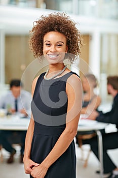 Shes going places in the company. Portrait of a smiling young businesswoman standing in a modern office.