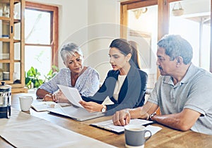 Shes going to help them make their savings last. a mature couple getting advice from their financial consultant at home.